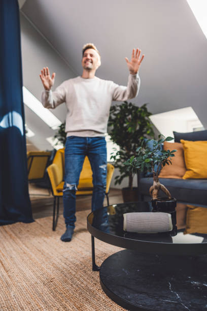 istock Man using smart devices in his living room. Smart speaker dancing, thermostat, tablet, robot vacuum cleaner, checking security cameras. 1817146468