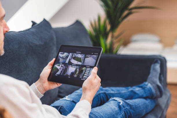 istock Man using smart devices in his living room. Smart speaker dancing, thermostat, tablet, robot vacuum cleaner, checking security cameras. 1817148619