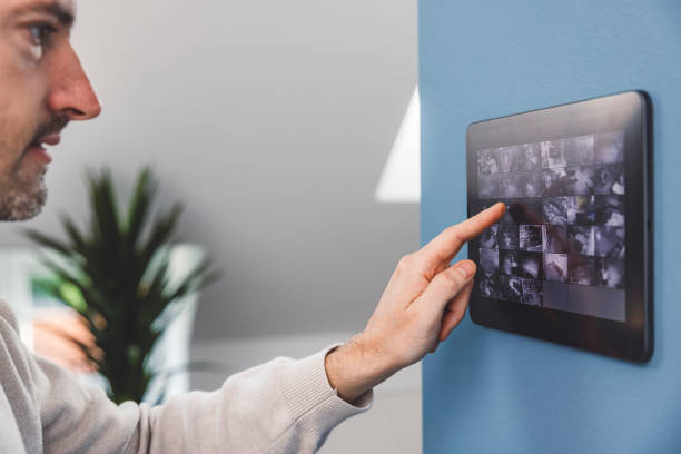 istock Man using smart devices in his living room. Smart speaker dancing, thermostat, tablet, robot vacuum cleaner, checking security cameras. 1817149288