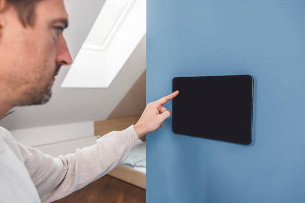 istock Man using smart devices in his living room. Smart speaker dancing, thermostat, tablet, robot vacuum cleaner, checking security cameras. 1817149311