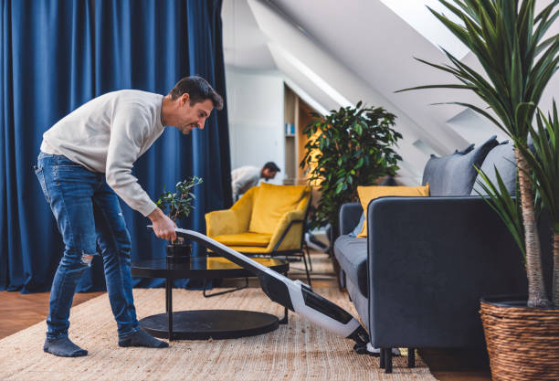 istock Man using smart devices in his living room. Smart speaker dancing, thermostat, tablet, robot vacuum cleaner, checking security cameras. 1817150886