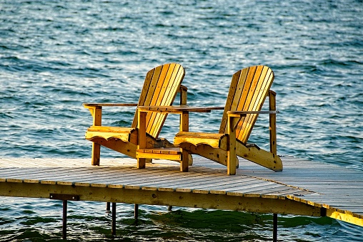 Adirondack Chairs on a Deck with a lake in the background