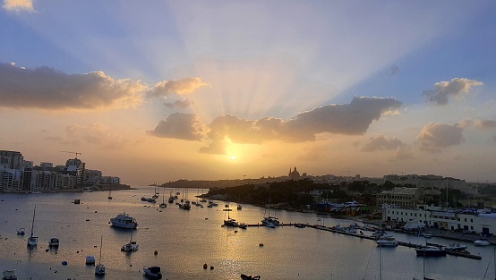 Seaview over the bay between Sliema and Valletta in the evening golden hour; boats floating on a calm water