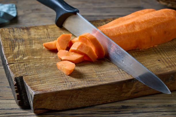 cenoura fresca crua fatiada - carrot close up silverware cutting board - fotografias e filmes do acervo