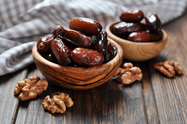 Dates fruit in a wooden bowl Dates fruit in a wooden bowl closeup on wooden background date fruit stock pictures, royalty-free photos & images