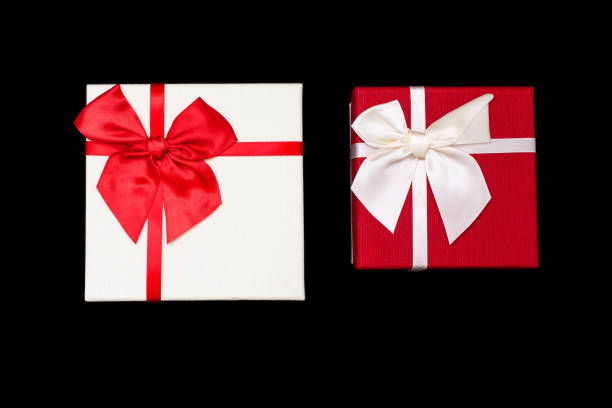 Two white and red gift boxes with ribbons and bows on a black background. Gifts for birthday or traditional holidays. Two beautiful gift boxes close up