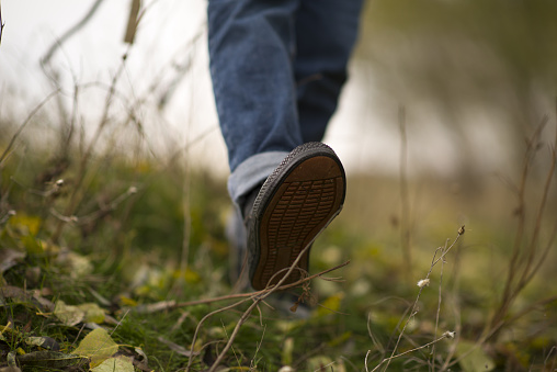 Young lady walking in the countryside in autumn and foot detail