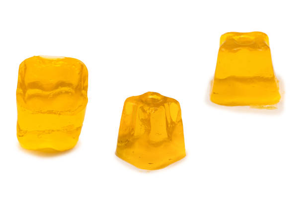 Closeup of a man's hand holding a generic, mass produced laundry pod against a white background.