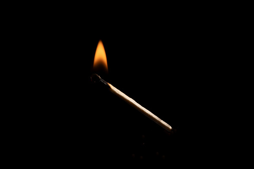 Lit and falling match on a black background.