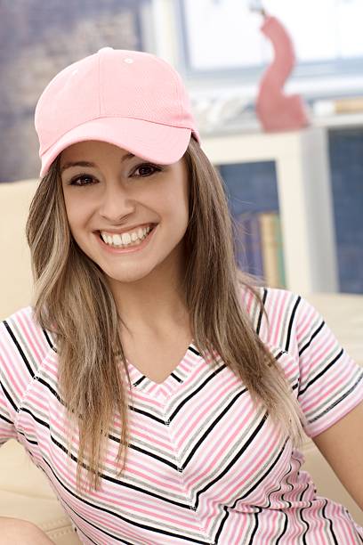 Sporty girl in baseball cap smiling Sporty girl smiling in pink baseball cap at home.. woman wearing baseball cap stock pictures, royalty-free photos & images