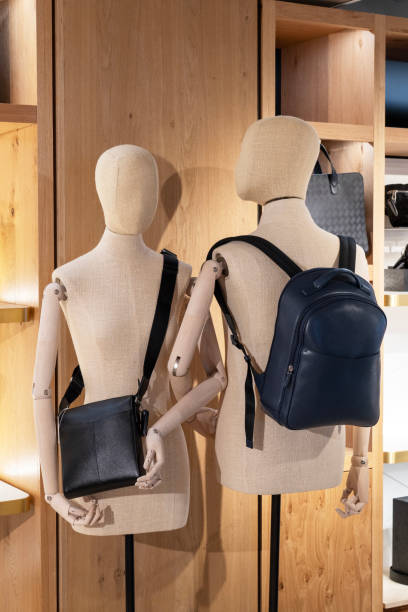 istock Back view of two mannequins with shoulder bags against a wooden panel backdrop. 1817244498