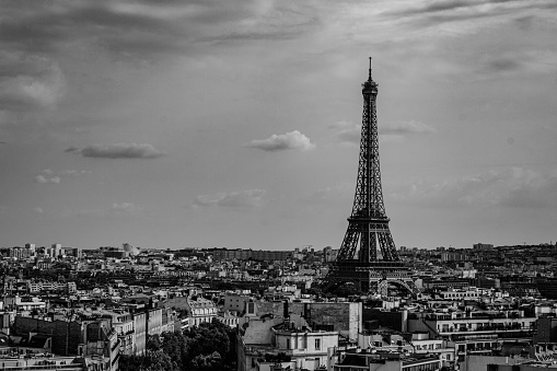 A dramatic black and white picture of the Eiffel Tower viewed from the Seine.