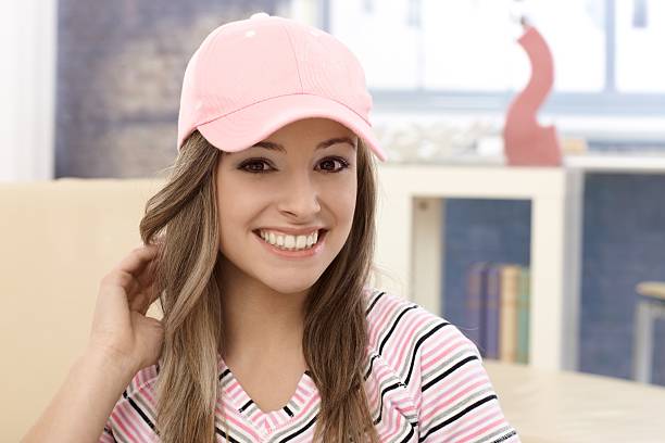 Portrait of young girl in baseball cap Portrait of smiling young girl in baseball cap, looking at camera.. woman wearing baseball cap stock pictures, royalty-free photos & images