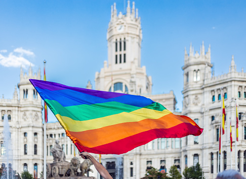Cibeles square, Madrid, Spain: Arm waving LGBTQIA flag in Cibeles Square in Madrid during the celebration of the gay pride parade in Madrid. The image represents a moment of visibility, acceptance, and affirmation of diversity in society in front of the City Hall building in Madrid located in the famous Cibeles Square.