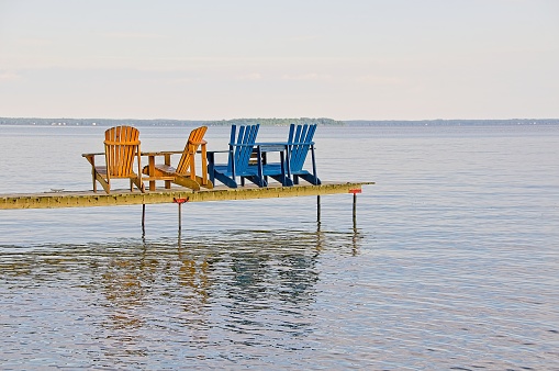 Adirondack Chairs on a Deck with a lake in the background