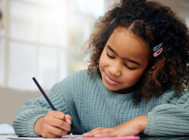 istock Happy child, school study and coloring with development and knowledge in home. Books, young girl and kitchen with creativity project and smile from student education and art with drawing at table 1817282628