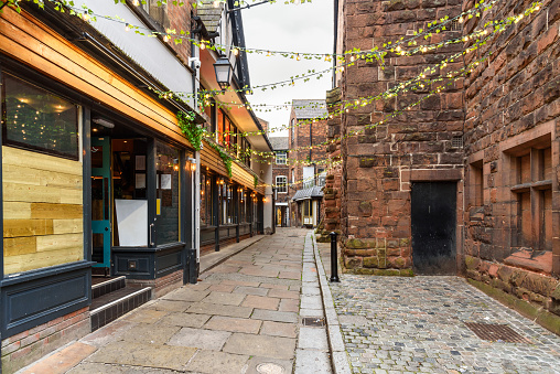 Deserted cobblestone alley lined with old stone buildings and restaurants in a historic central district. Chester, England, UK.