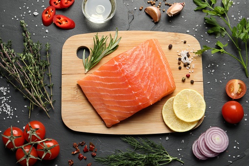 Fresh raw salmon and ingredients for marinade on black table, flat lay