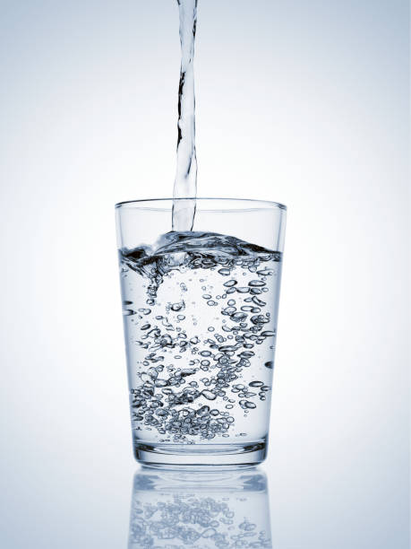 istock Water pouring in a glass with bubbles on blue background 1817320081