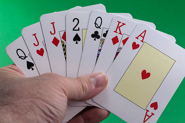 istock Hand holding a royal flush hearts on green 181732335