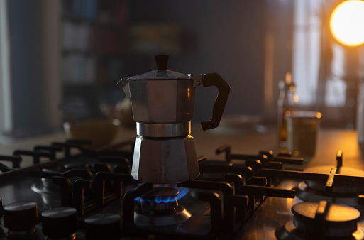 Traditional italian coffeemaker on a gas stove in a kitchen, moody morning light