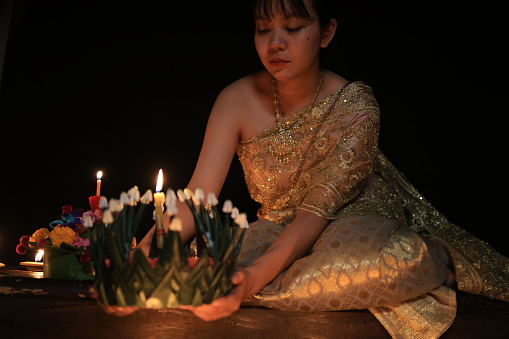 A  young  woman wearing an ancient Thai dress on the day of the Loi Krathong Festival with a black background
