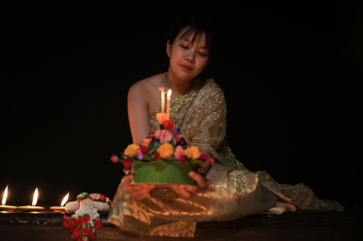 A  young  woman wearing an ancient Thai dress on the day of the Loi Krathong Festival with a black background