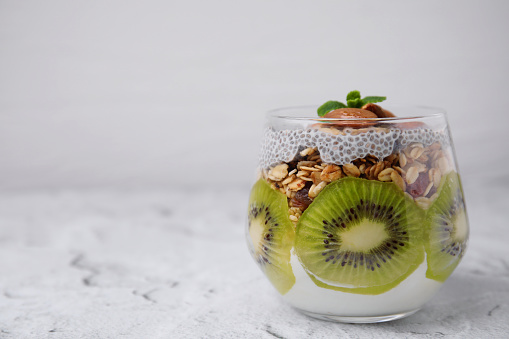 Delicious dessert with kiwi, chia seeds and almonds on light textured table, space for text