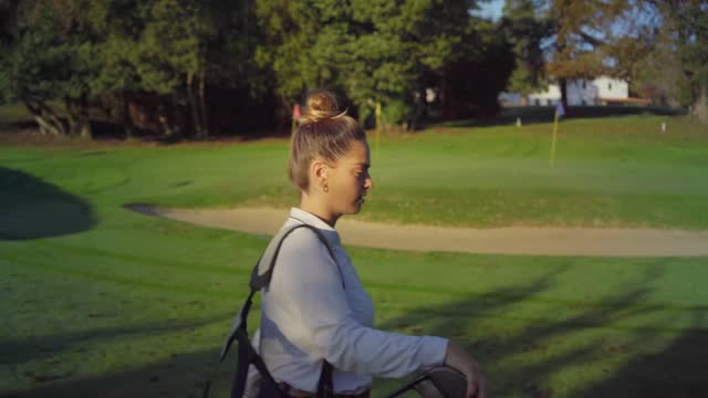 Side view of a young golfer walking carrying golf bag