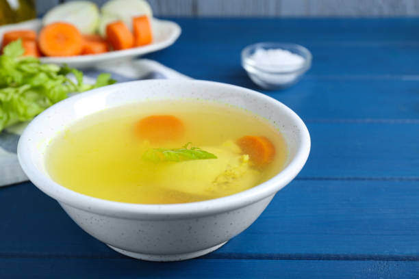 istock Delicious chicken bouillon with carrot and celery on blue wooden table, closeup 1817372367