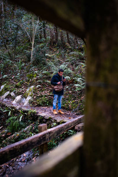 istock Autumn woods: man on footbridge, phone. 1817374950