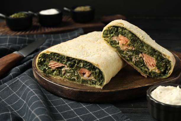 istock Tasty strudel with salmon and spinach on black wooden table 1817385270