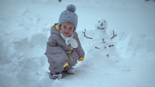 Portrait of girl with snowman in deep snow.