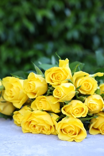 Beautiful bouquet of yellow roses on light table outdoors. Space for text