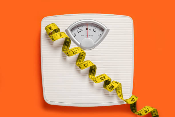 istock Bathroom scale and measure tape on orange background, top view 1817474112