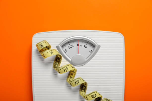 istock Bathroom scale and measure tape on orange background, top view 1817474123