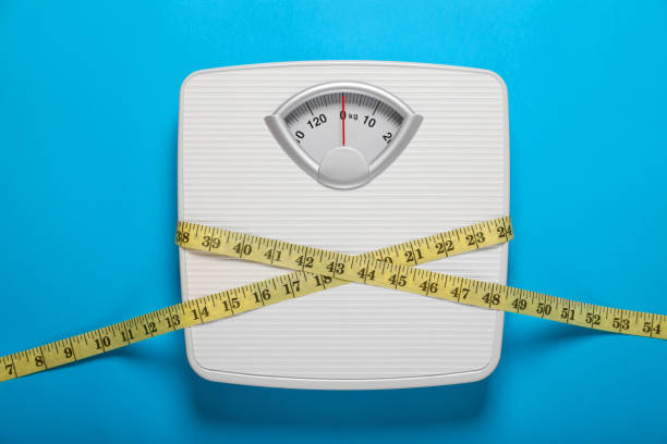 istock Bathroom scale tied with measure tape on light blue background, top view 1817474630