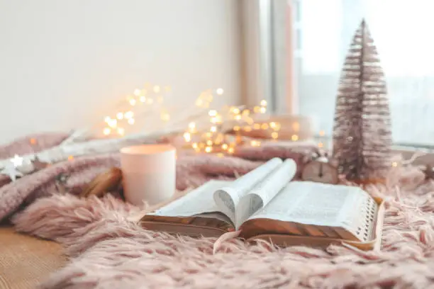 Photo of Open Bible in cozy pink winter home morning atmosphere