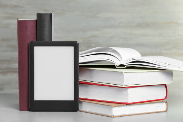istock Portable e-book reader and many hardcover books on white textured table 1817498006