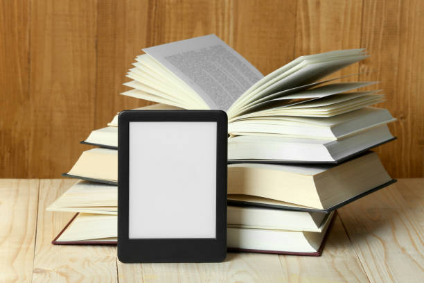 istock Portable e-book reader and open hardcover books on wooden table 1817498008