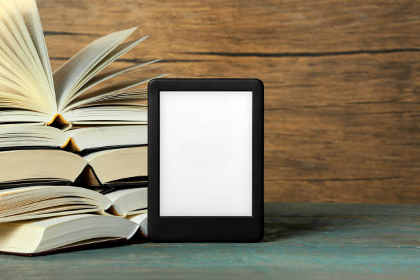 istock Portable e-book reader and open hardcover books on wooden rustic table, space for text 1817498012