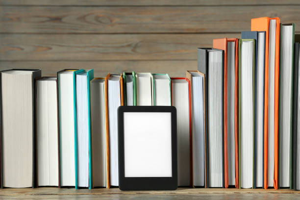 istock Portable e-book reader and many hardcover books on wooden table 1817498534
