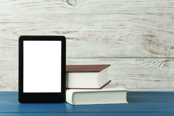 istock Portable e-book reader and hardcover books on blue wooden table, space for text 1817498536