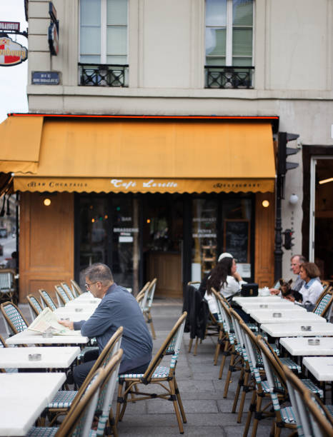 paris, france: senior man sits outside cafe with newspaper - notre dame de lorette imagens e fotografias de stock