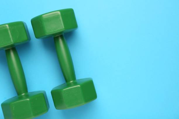 istock Green dumbbells on light blue background, flat lay. Space for text 1817508580