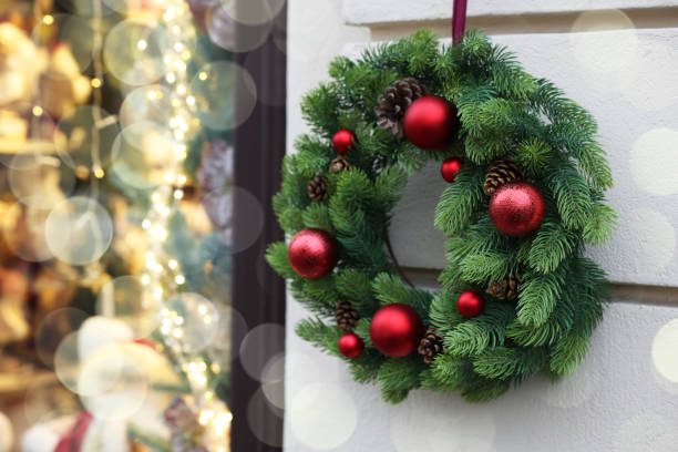 istock Beautiful Christmas wreath hanging on white building wall outdoors, space for text 1817519044