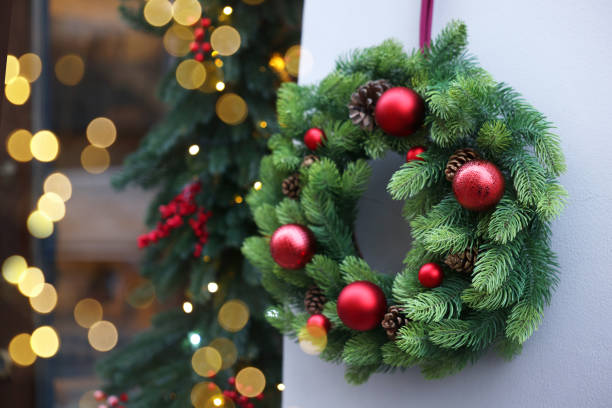 Beautiful Christmas wreath hanging on building wall outdoors, space for text