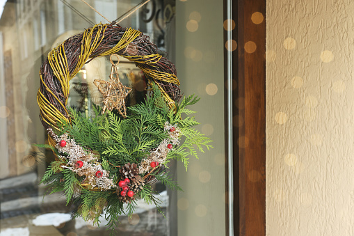 Beautiful Christmas wreath hanging on glass door, space for text
