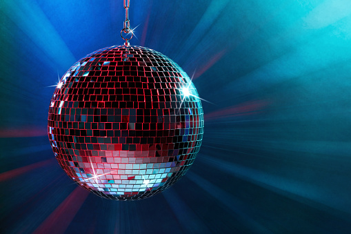 Shiny disco ball under blue lights, space for text