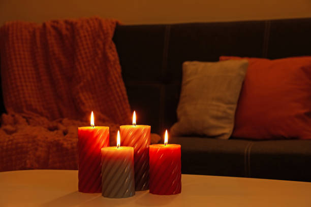 Beautiful candles on white table near sofa indoors. Cosy atmosphere